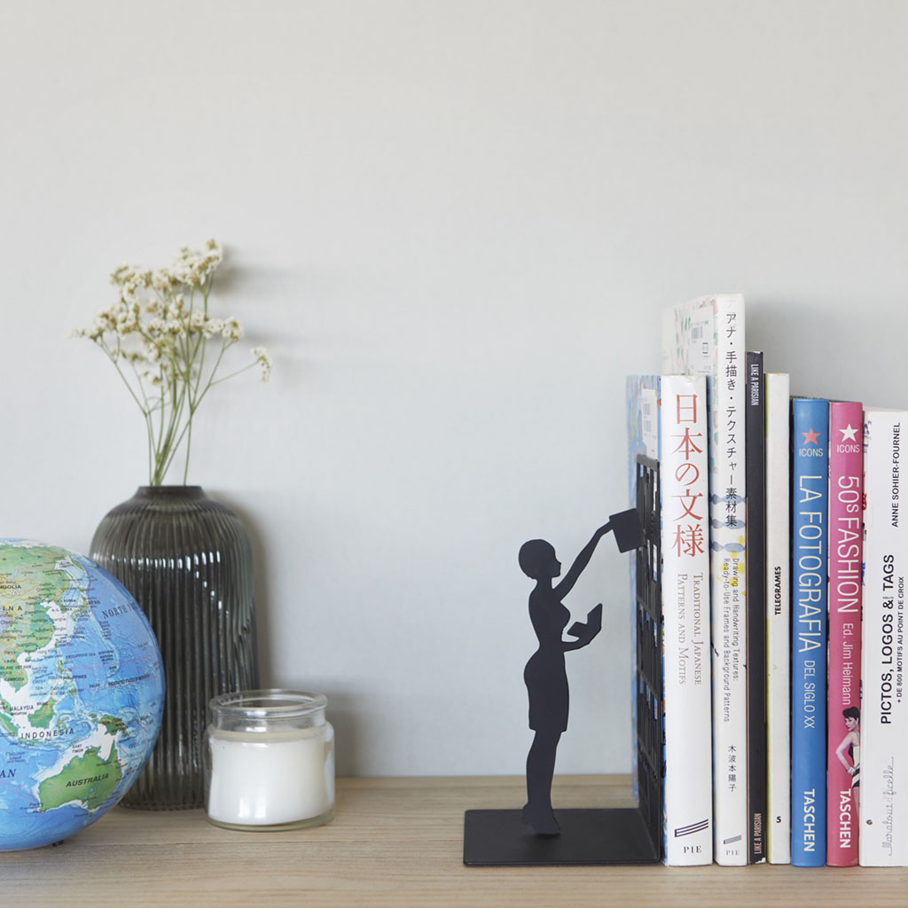 Un librero con libros al lado de un florero